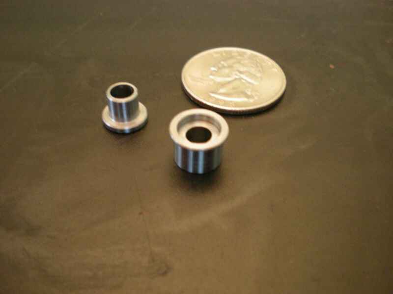 Two small metal pieces next to a quarter on a black surface