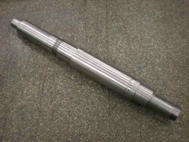 A metal shaft is sitting on a gray surface.