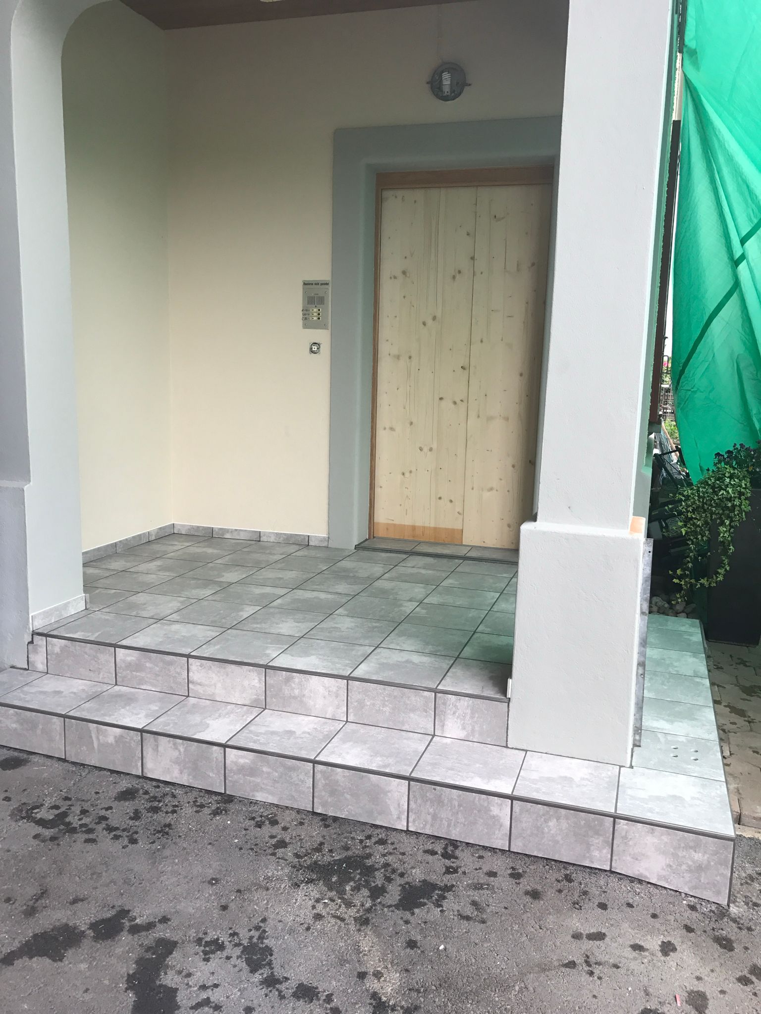 Eine Veranda mit Treppe, die zu einer Holztür hinaufführt.