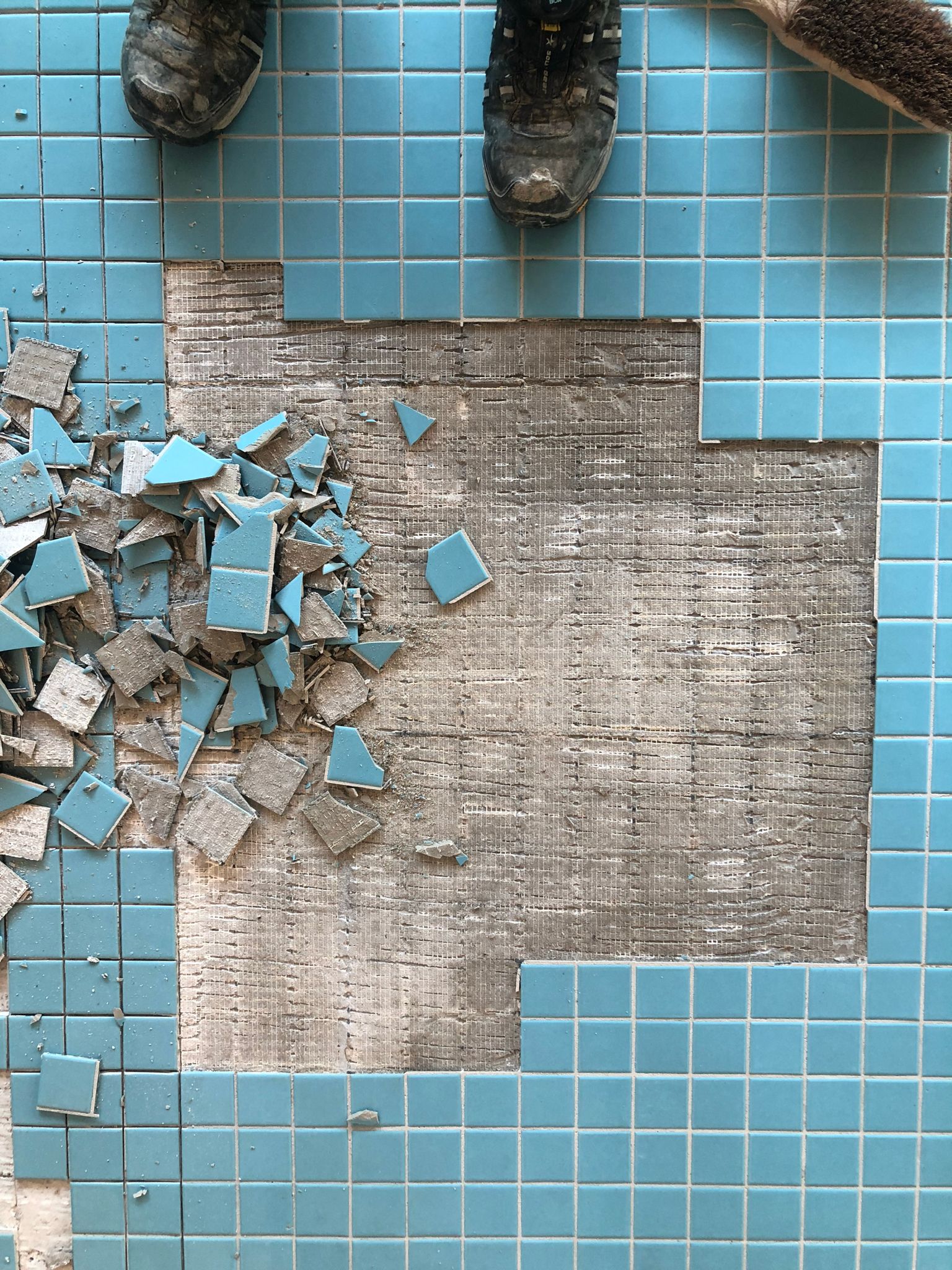 Eine Person steht auf einem Fliesenboden mit kaputten Fliesen