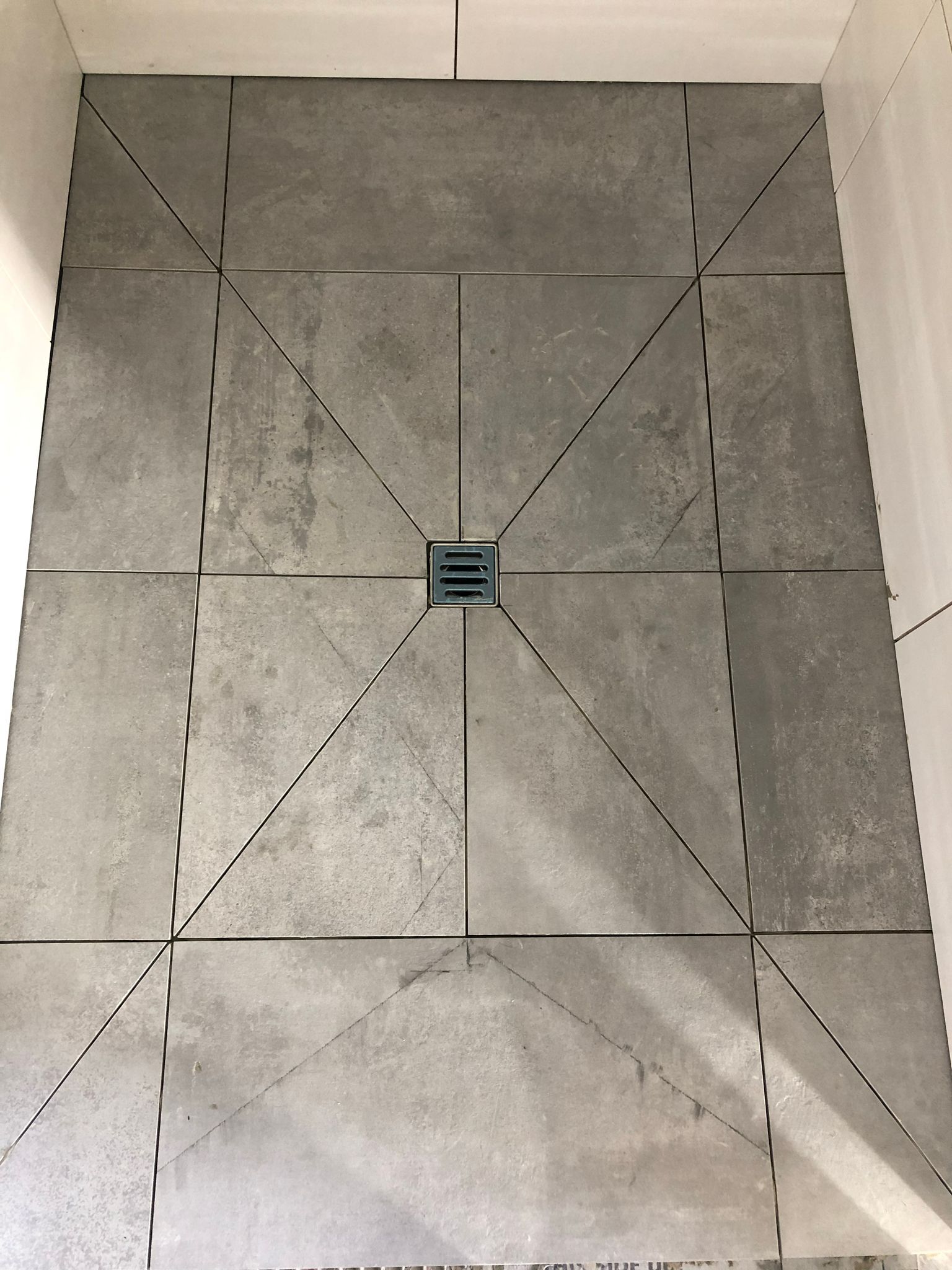 Eine Duschkabine mit einem Abfluss in der Mitte.