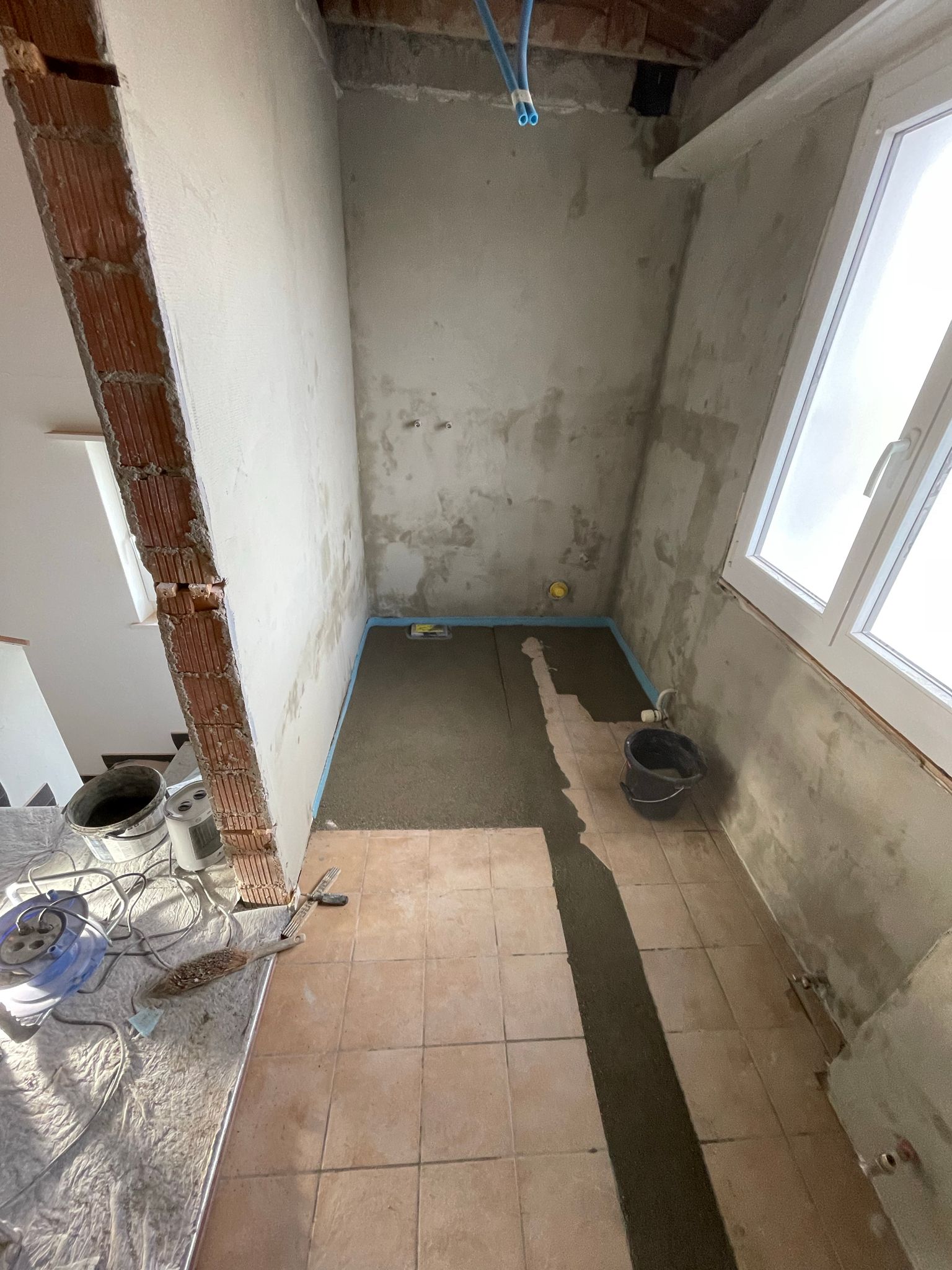 Ein im Bau befindliches Badezimmer, in dem gerade Fliesen auf dem Boden verlegt werden.