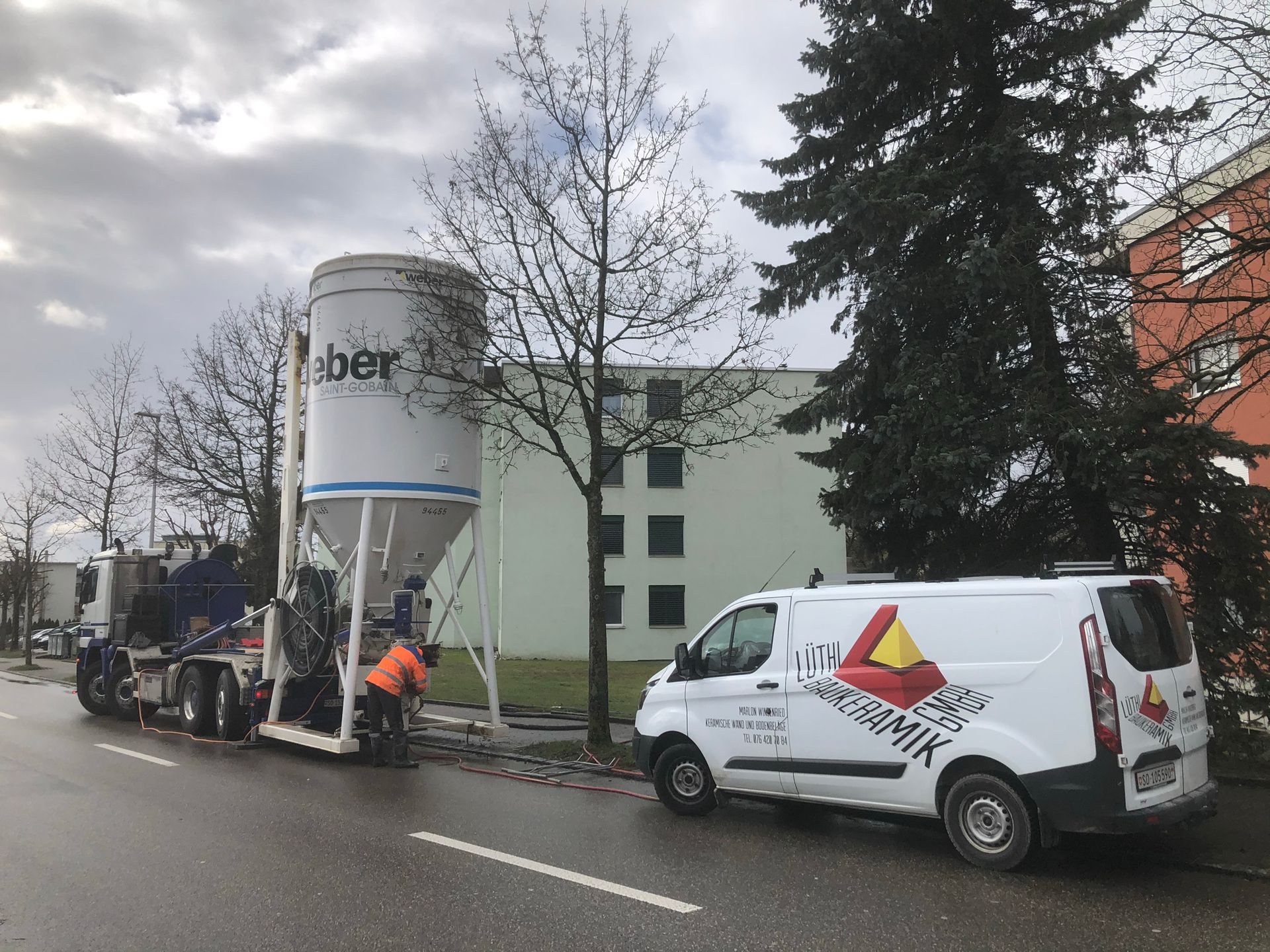 Ein weißer Lieferwagen parkt am Straßenrand neben einem Betonsilo.