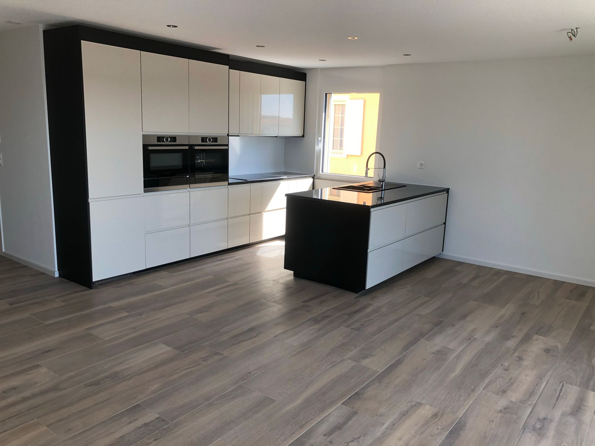 Eine leere Küche mit weißen Schränken und einer schwarzen Insel