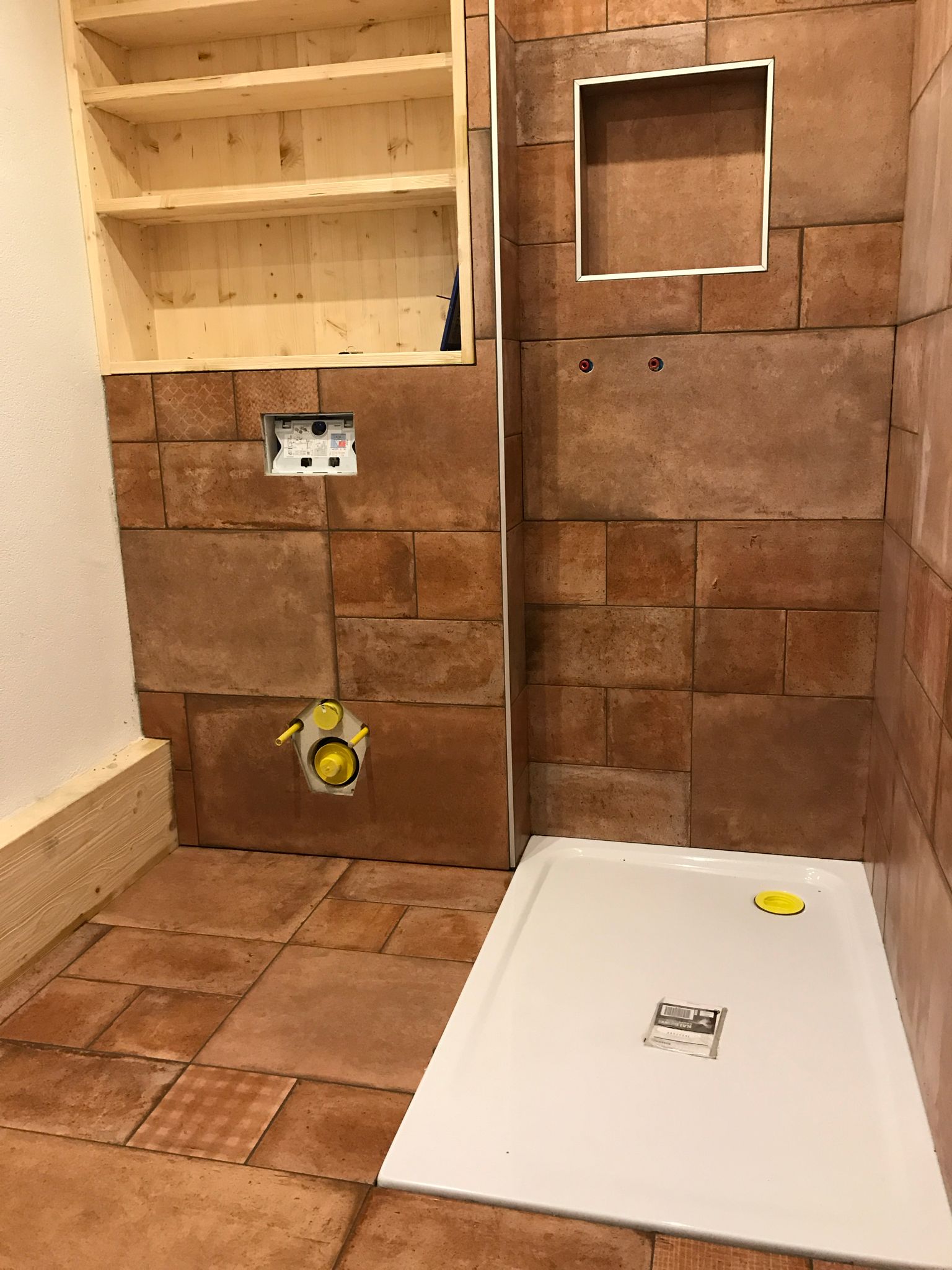 Ein Badezimmer mit ebenerdiger Dusche und einer Ziegelwand.