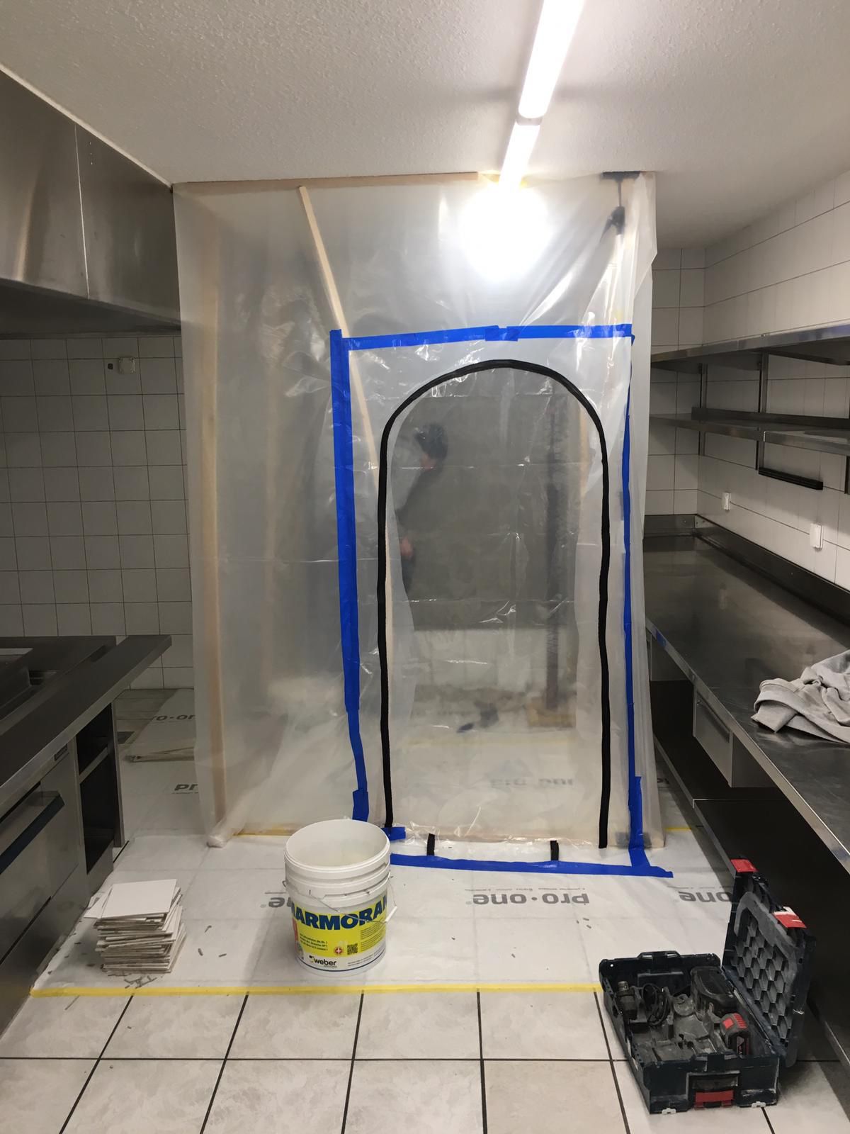 Eine Küche mit einem Eimer Farbe und einem Werkzeugkasten auf dem Boden.