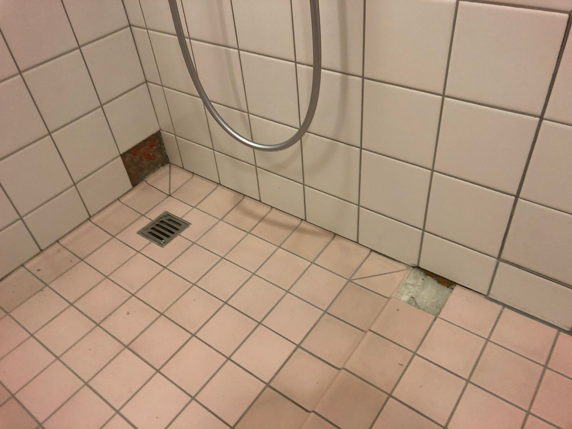 Ein Badezimmer mit rosa Fliesen und einem Duschkopf