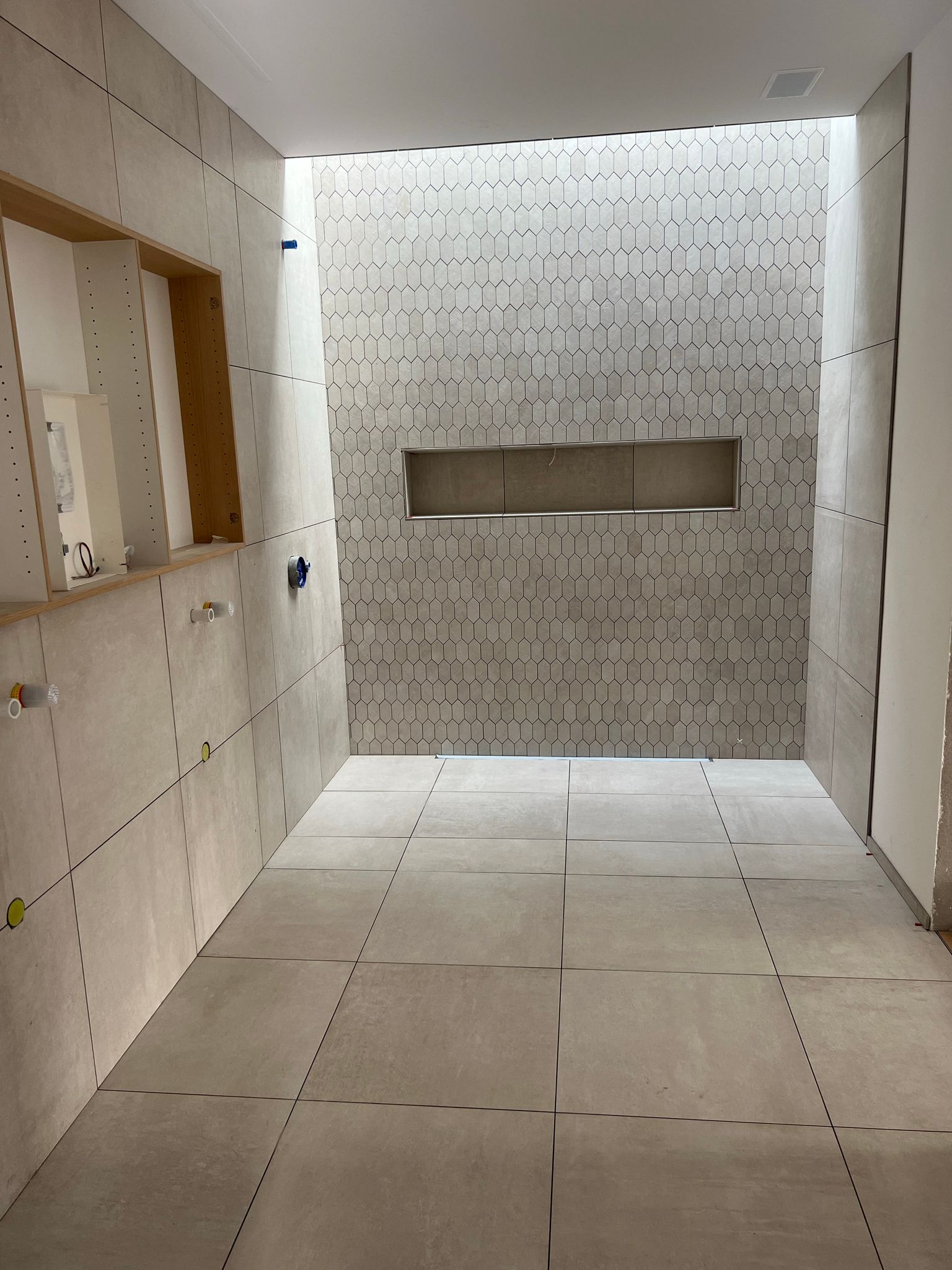 Ein langer Flur mit weißen Fliesen auf Boden und Wänden.