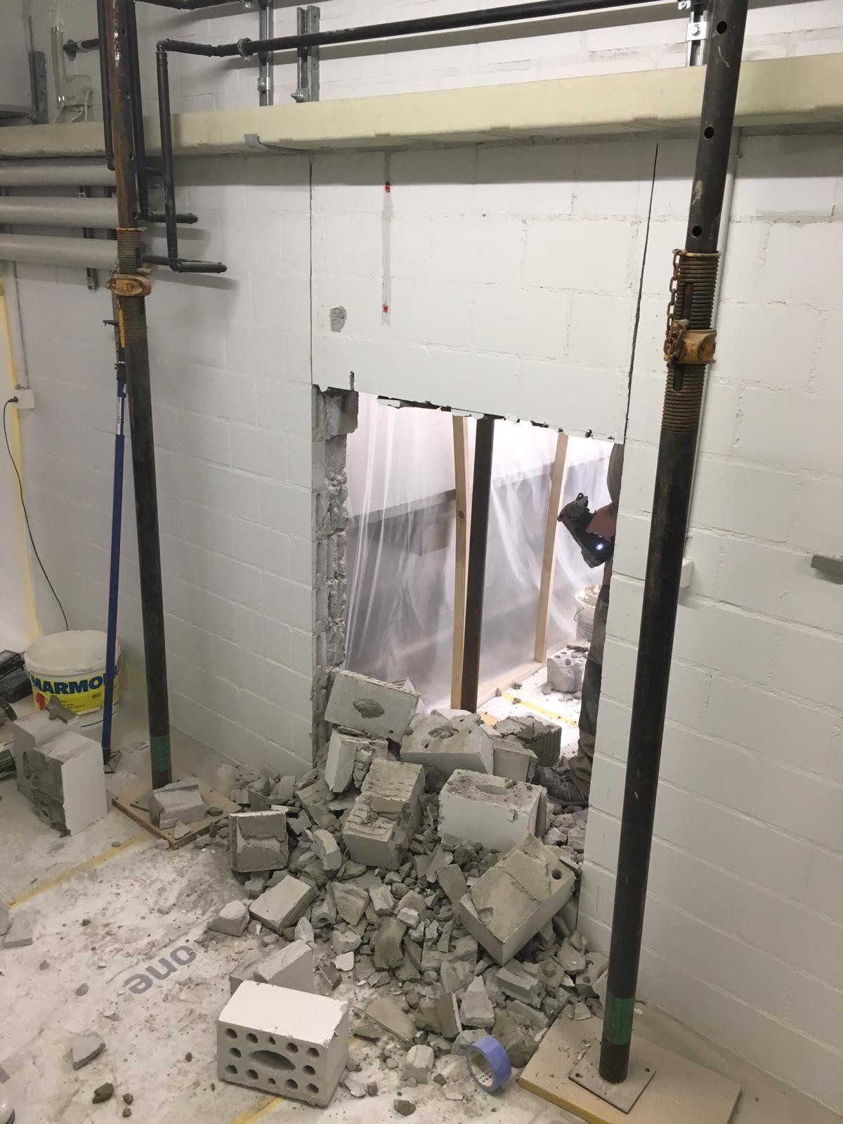 Ein Raum mit einem Loch in der Wand und Ziegeln auf dem Boden.