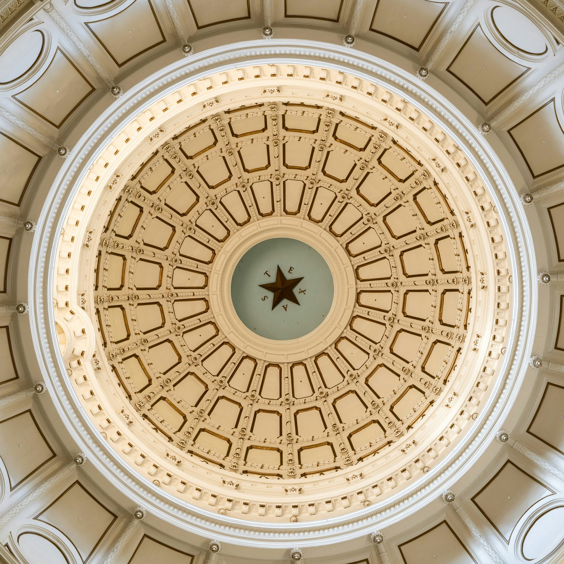 Texas State Capitol dome interior, looking upwards at intricate architectural details and a central Lone Star.