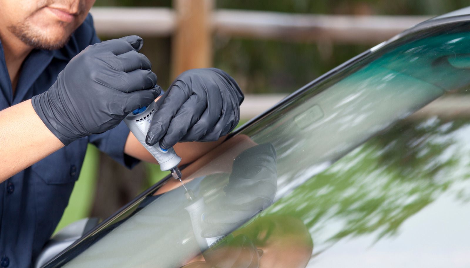 A man is repairing a windshield on a car.