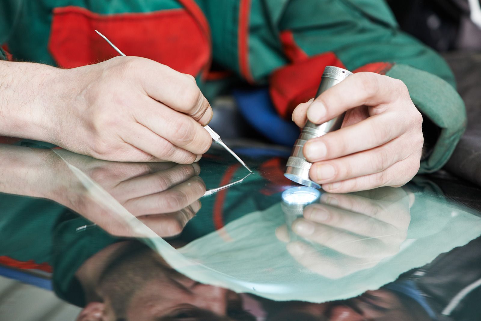 A man is working on a windshield with a tool.