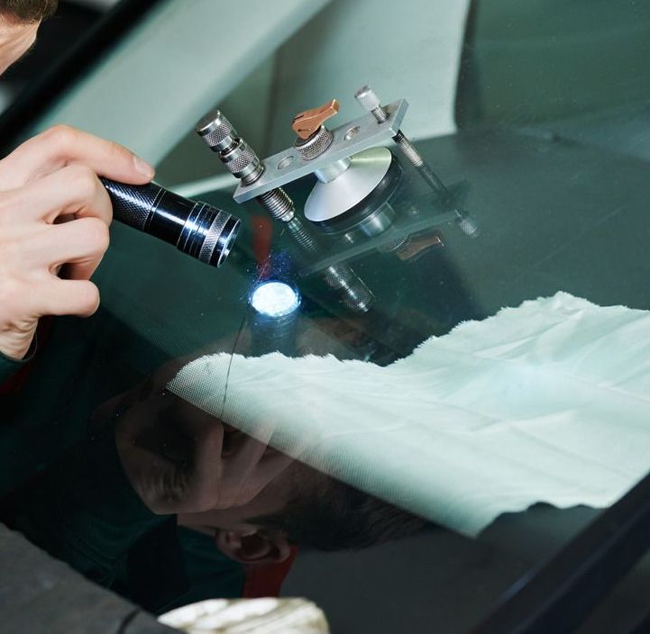 A man is working on a windshield with a flashlight