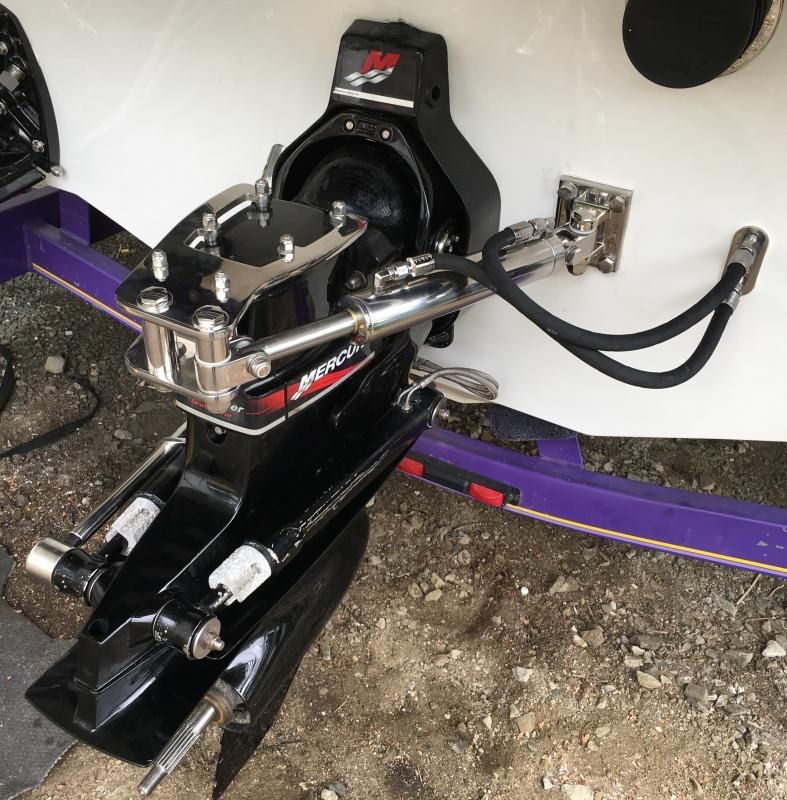 Black boat engine with purple accents attached to the hull, resting on gray concrete.