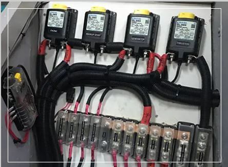Electrical panel with black components, red and black wiring, and a display screen.