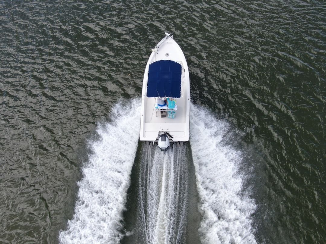 White boat with blue canopy speeding across water, creating a frothy wake.