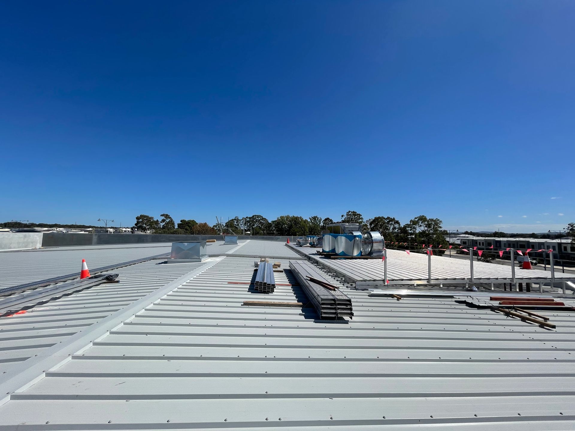 Two workers in safety vests and helmets install solar panels on a rooftop.