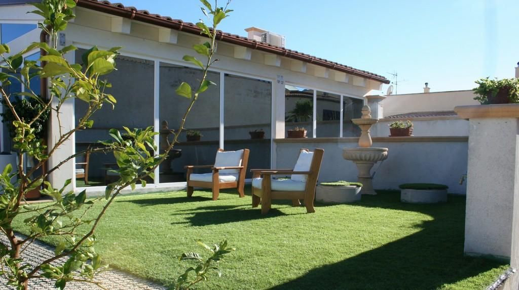 Porta bianca leggermente socchiusa in un portone grigio, ferramenta nera, pavimento piastrellato nero e grigio.