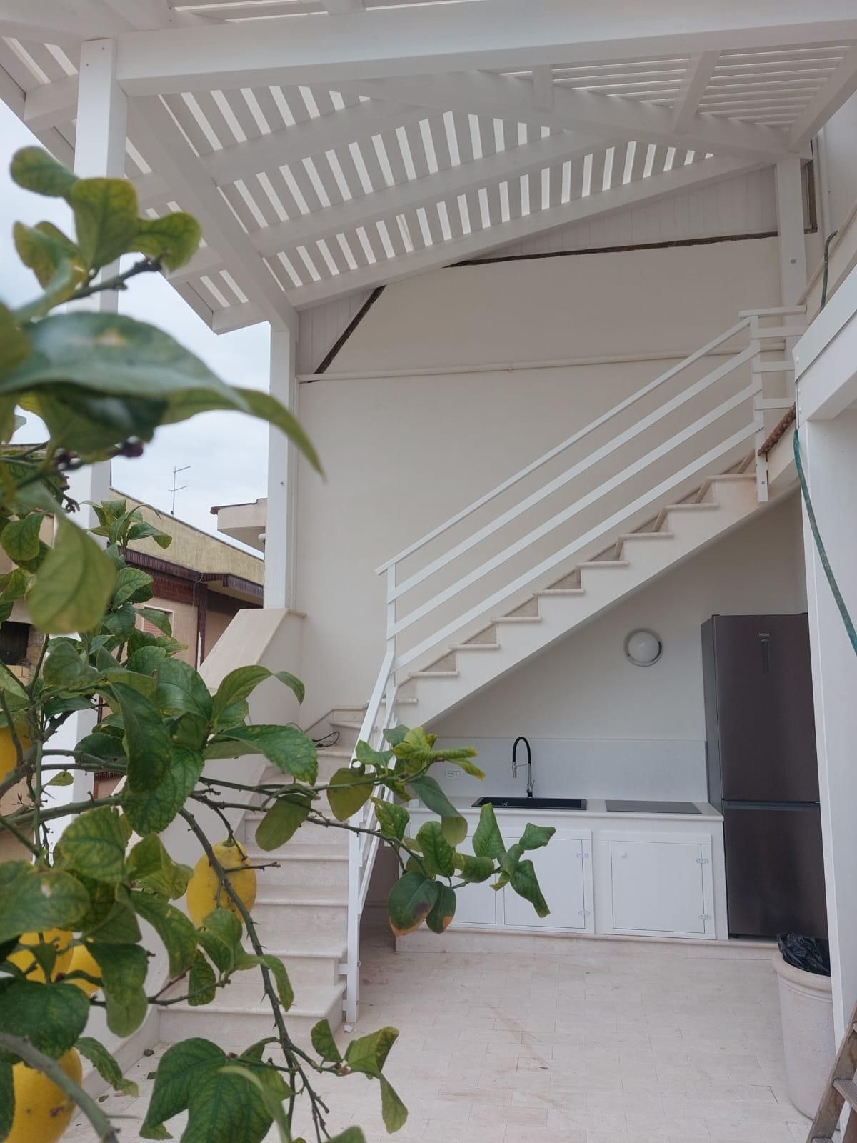 Famiglia di tre persone vicino a una finestra, che guarda fuori. Bambino in braccio, giornata di sole.