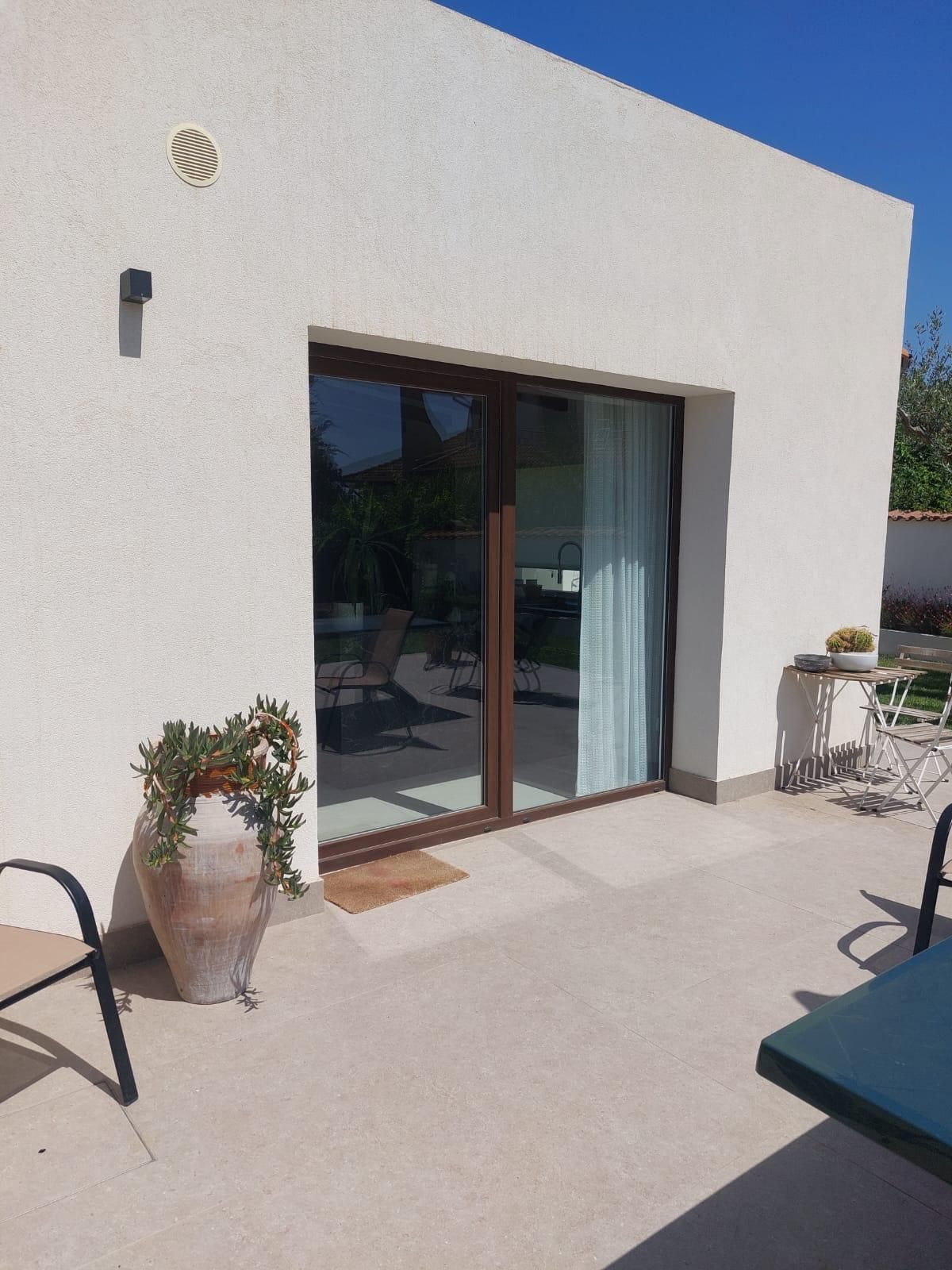 Porta bianca leggermente socchiusa in un portone grigio, ferramenta nera, pavimento piastrellato nero e grigio.