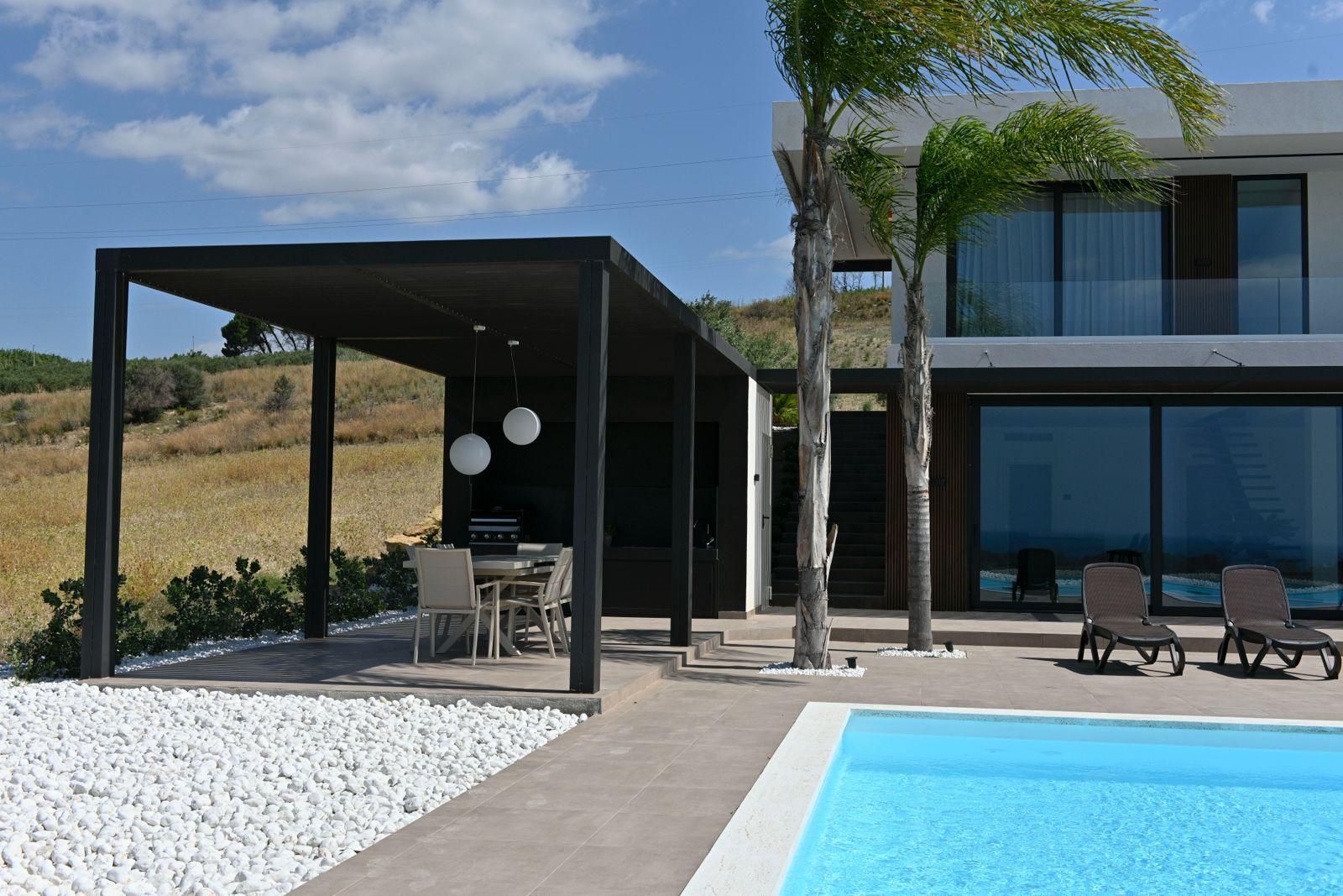 Infissi in legno, parzialmente aperti, che rivelano il cielo azzurro e un albero.