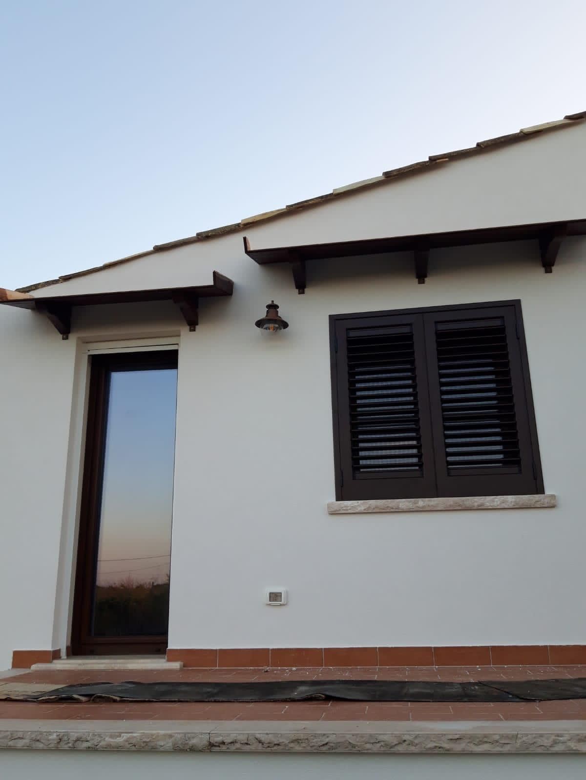 Casa in costruzione, vista esterna, con impalcature e facciata incompiuta, contro un cielo nuvoloso.