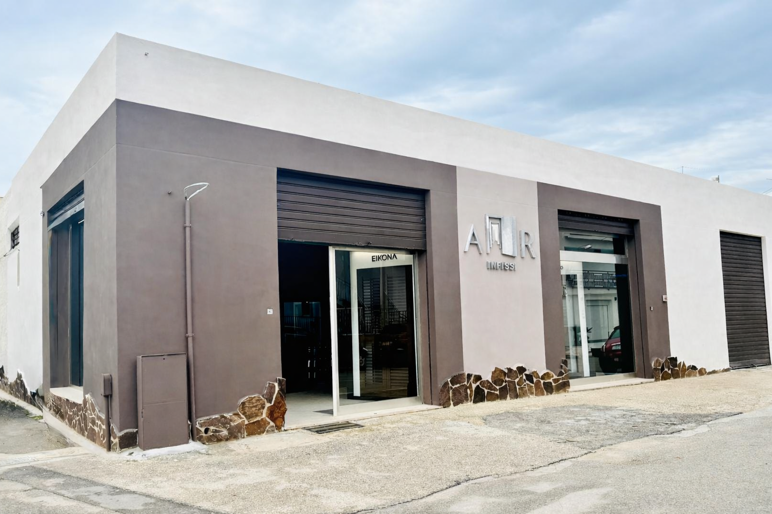 Recinzione in listelli bianchi con cancello; cesti di fiori; facciata in mattoni.