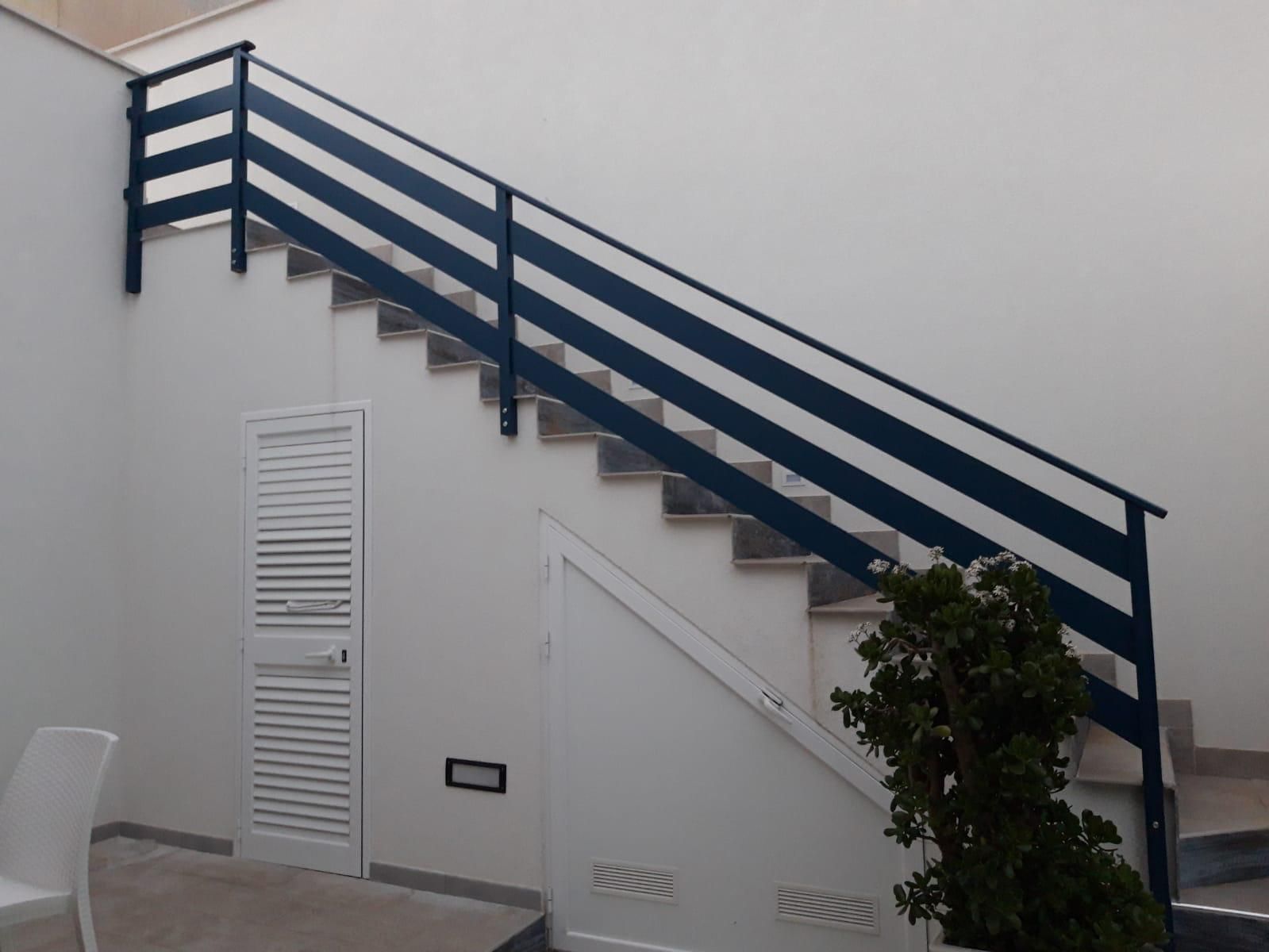 Scala con gradini in legno e ringhiera in metallo, accanto a una finestra con vista sull'esterno.