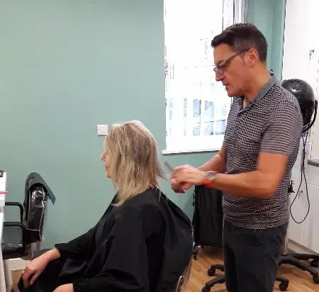 A man is cutting a woman 's hair in a salon.
