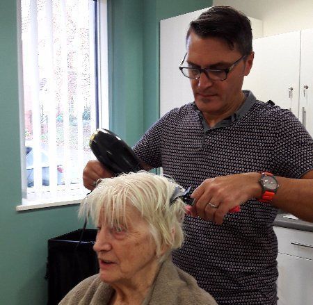 A man is blow drying a woman 's hair in front of a window.