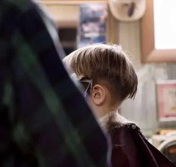 A young boy is getting his hair cut by a barber.