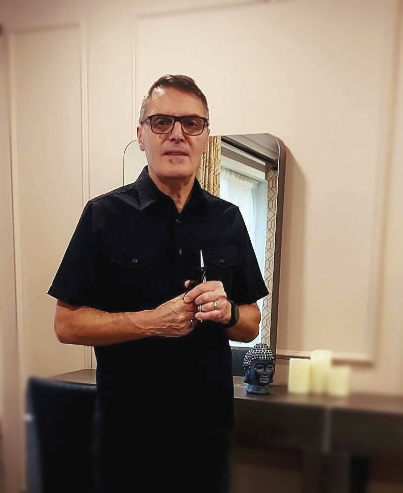 A man is sitting in a chair in front of a sink in a salon.