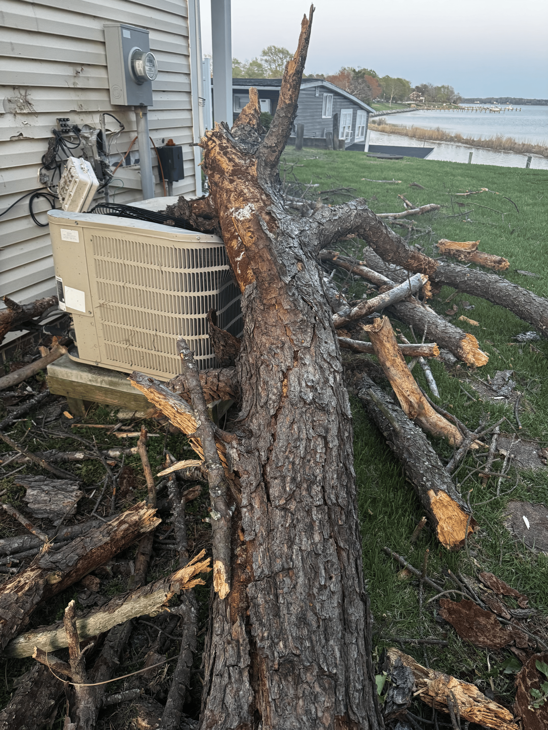 damaged exterior home broken HVAC unit tree fallen through home