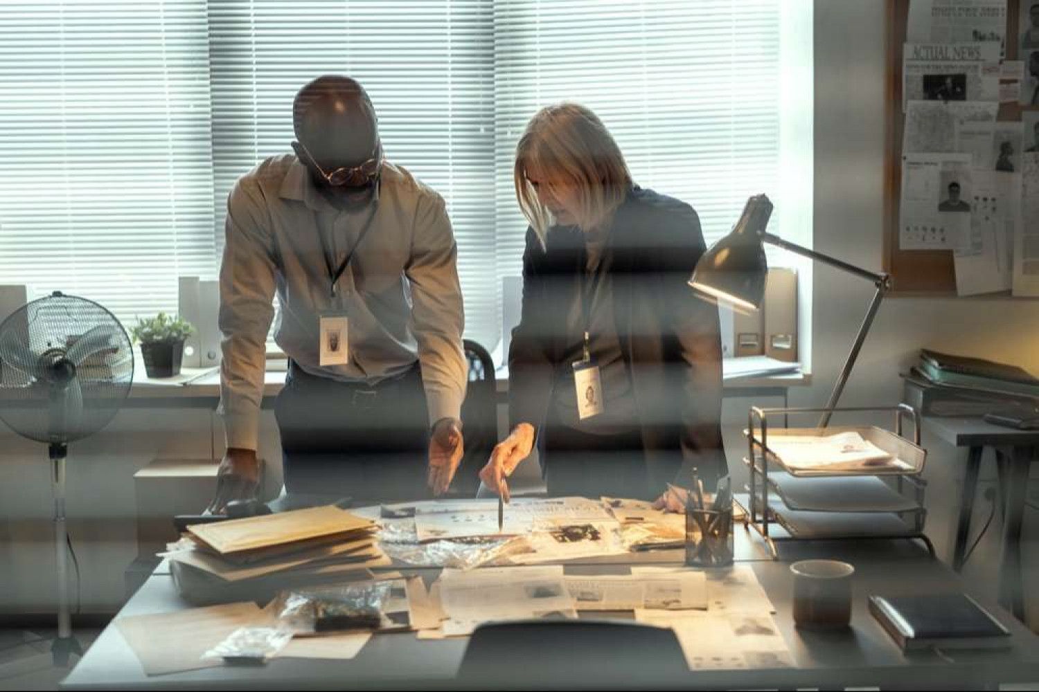 A man and a woman are standing at a desk looking at papers.