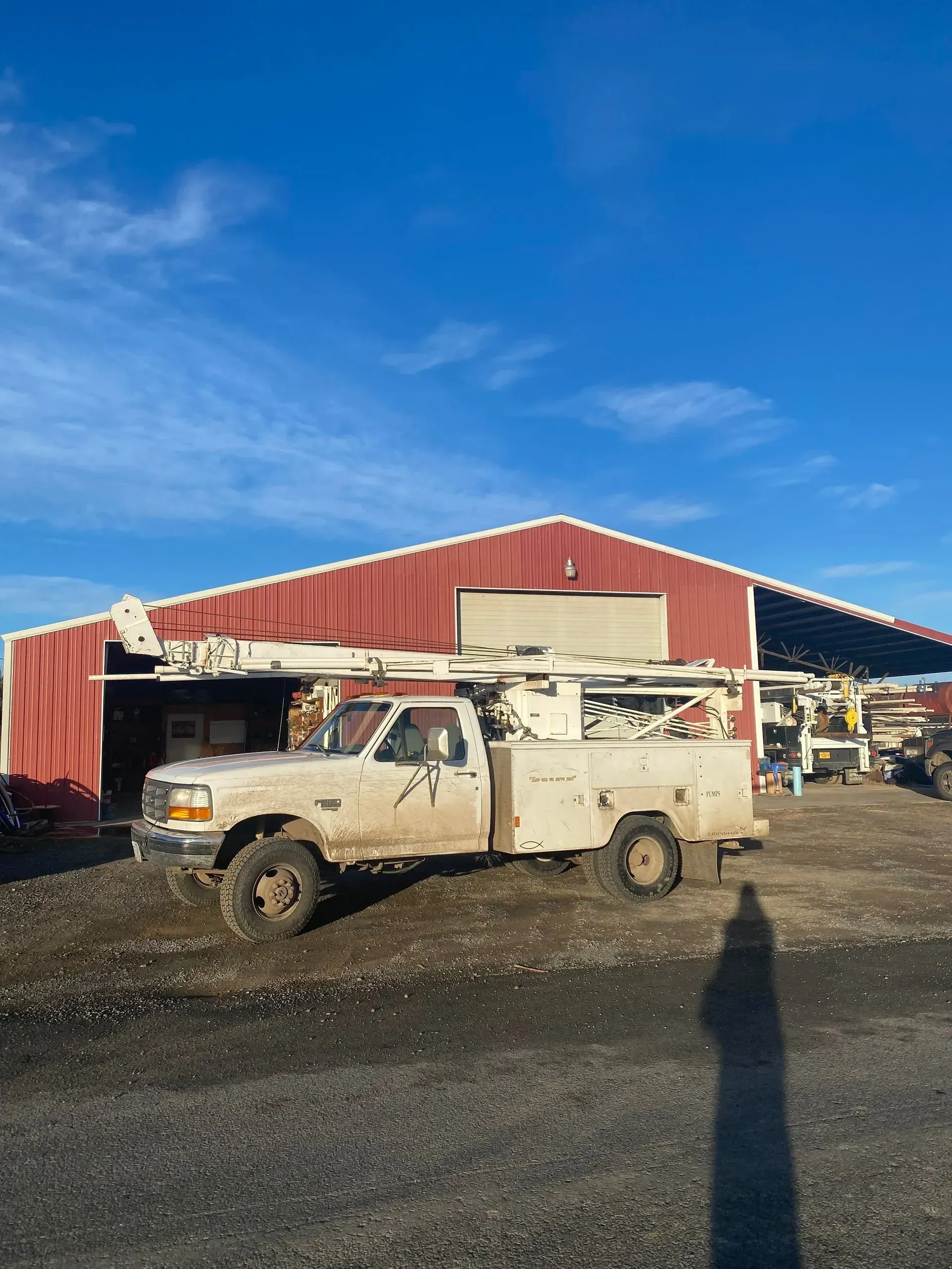 A white truck is parked in front of a red building.
