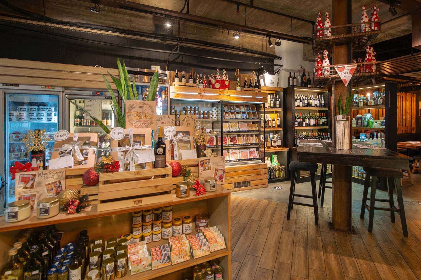 Retail display of artisanal products at Cartel Deli with wooden shelving and bar seating