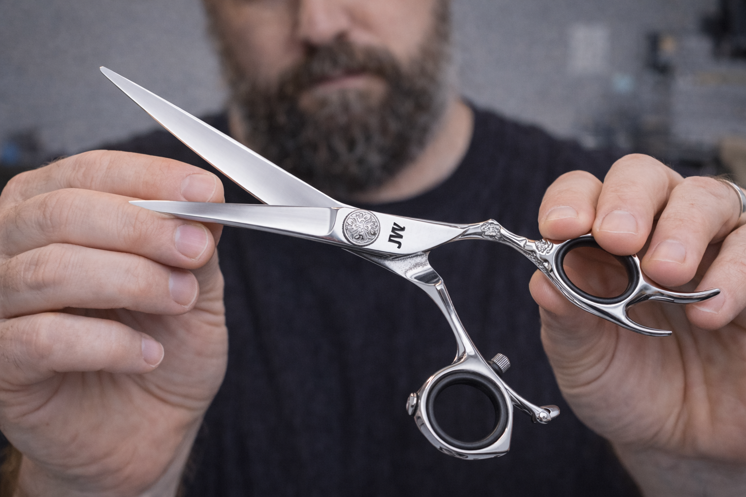 Person using a magnifying glass to inspect a pair of open scissors, checking the sharpness, on a blue cloth.