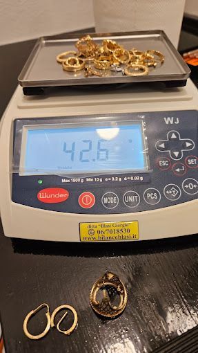 Un vassoio di gioielli d'oro viene pesato su una bilancia.