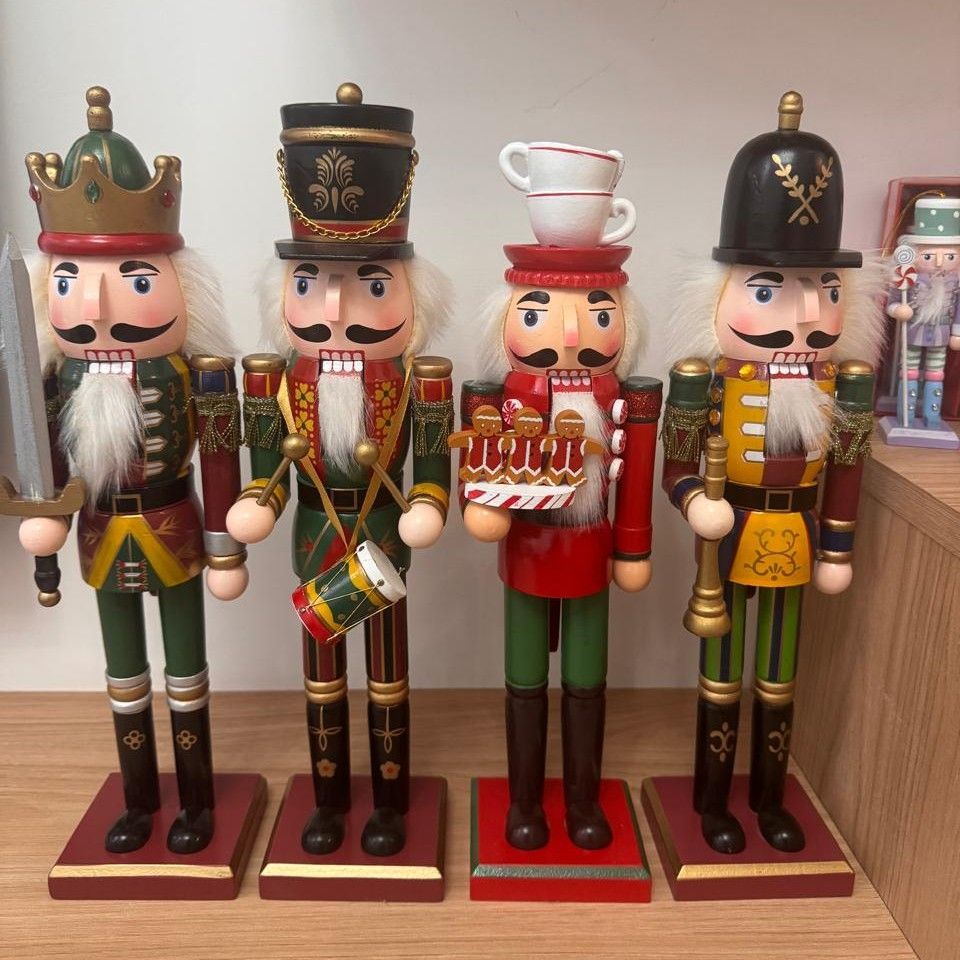 Cuatro coloridas figuras de cascanueces sobre un estante. Cada una con un uniforme y un sombrero diferentes.