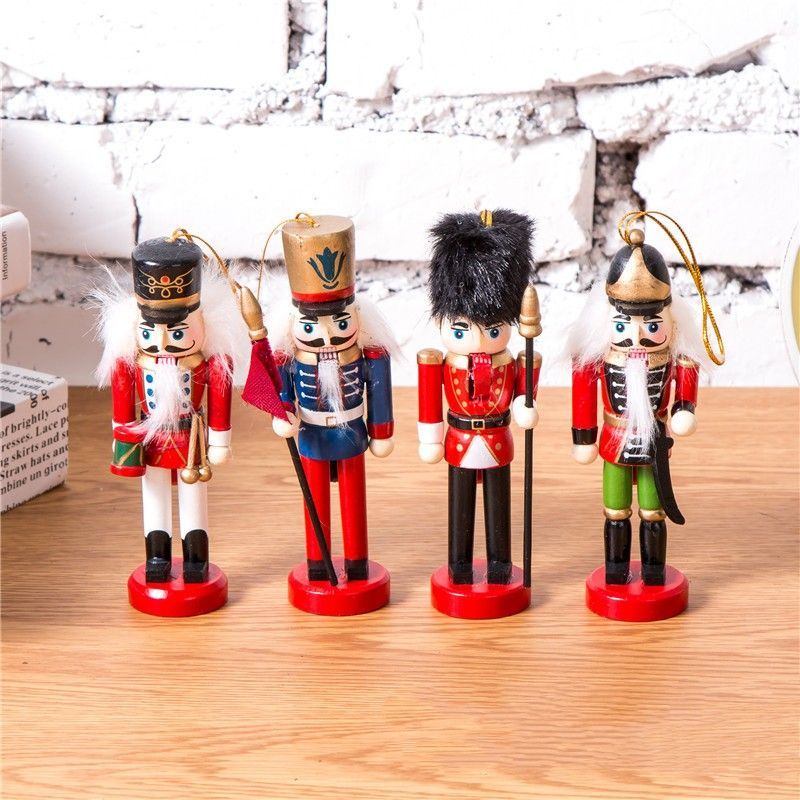 Cuatro figuras de cascanueces en miniatura, uniformes, con detalles en rojo y azul, sobre una superficie de madera.