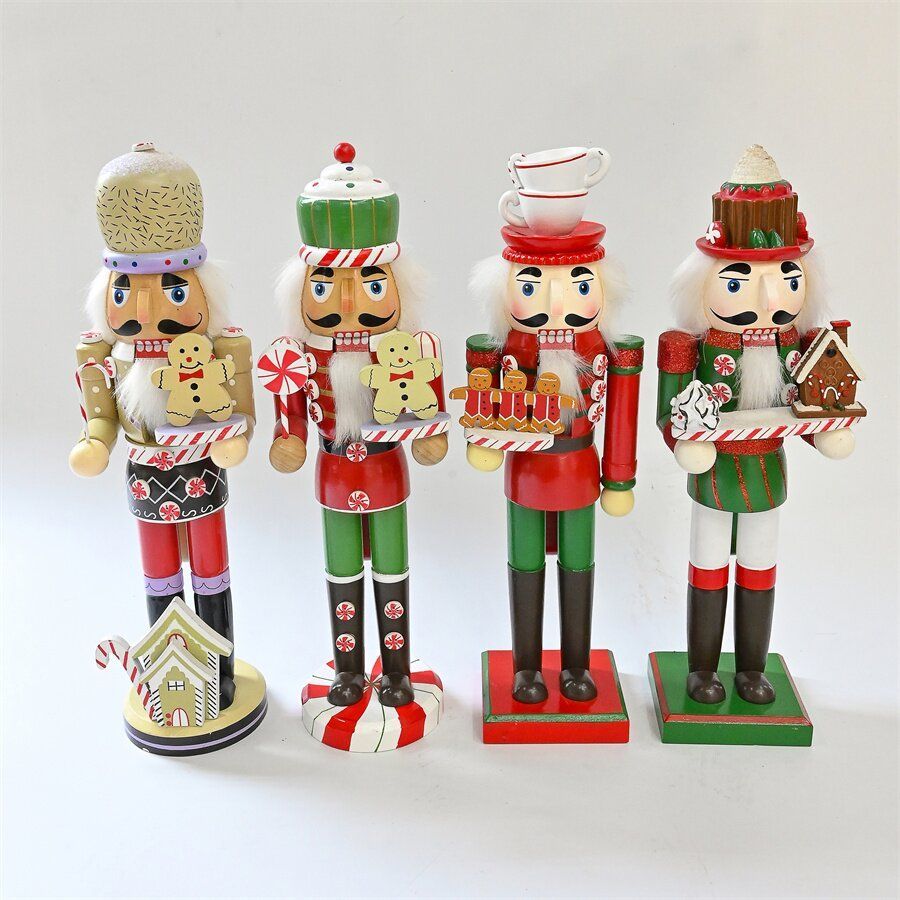 Cuatro figuras festivas de cascanueces, cada una con un dulce navideño en miniatura.