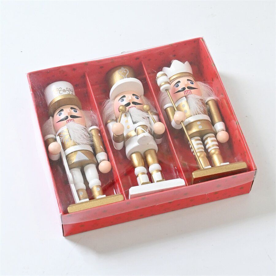 Tres cascanueces blancos y dorados en una caja roja, para decoración navideña.