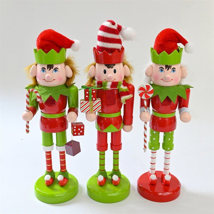 Tres elfos cascanueces con trajes rojos y verdes, sosteniendo regalos y bastones de caramelo, sobre un fondo blanco.