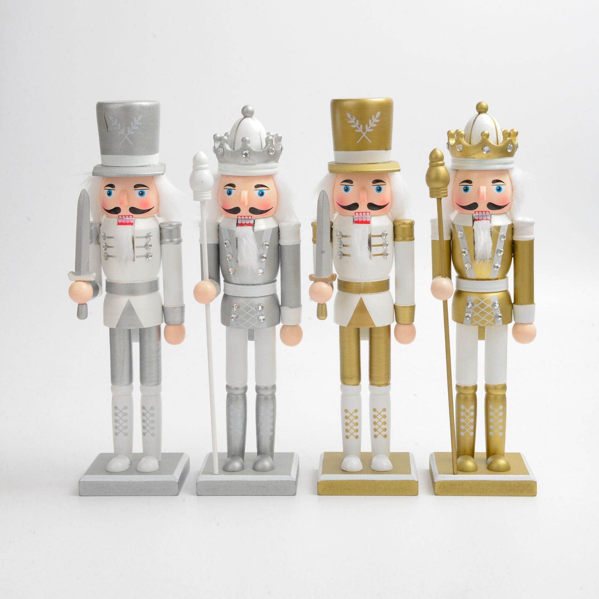 Cuatro figuras decorativas de cascanueces en plata y oro, sobre fondo blanco.