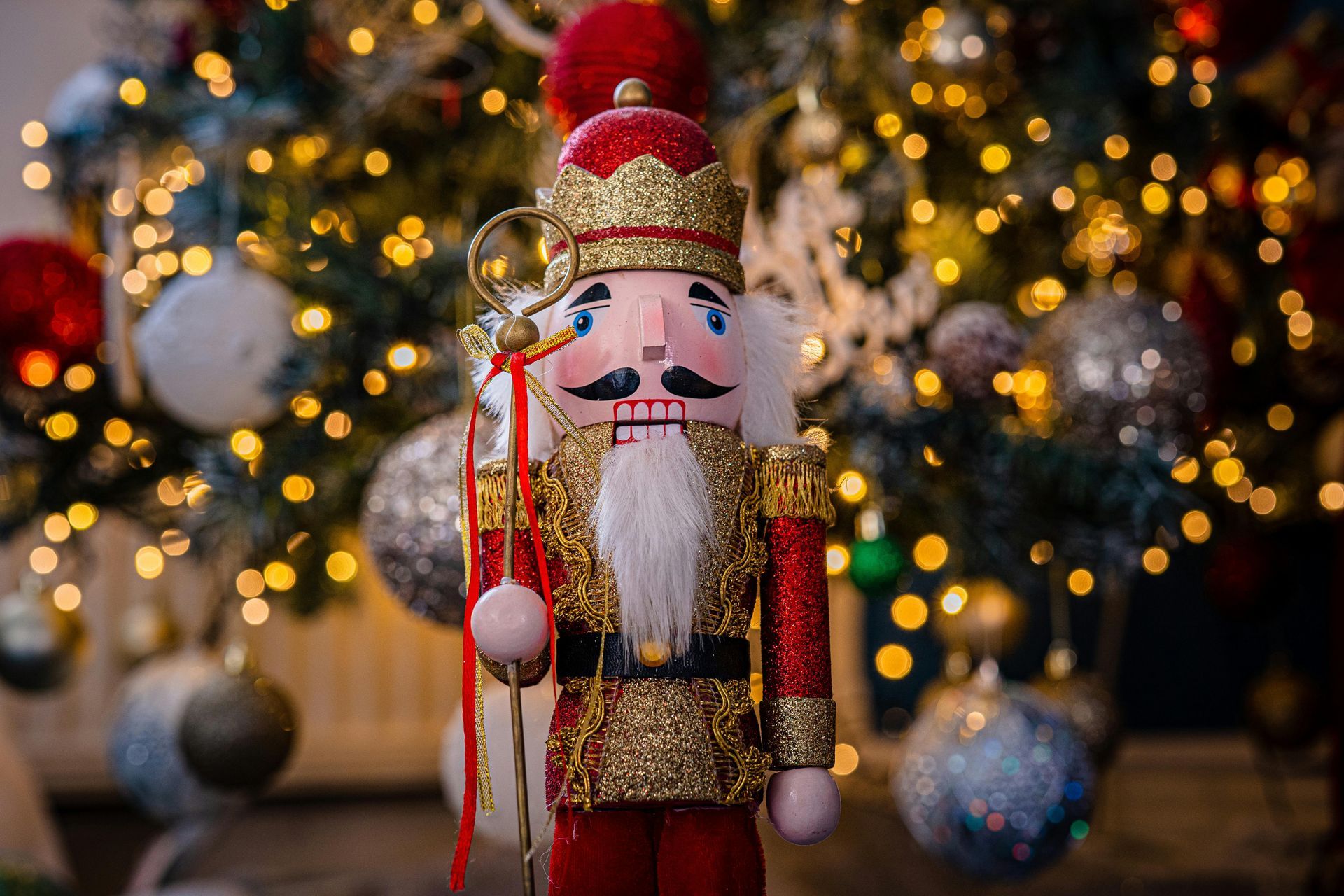 Figura de cascanueces delante de un árbol de Navidad decorado con adornos y luces.