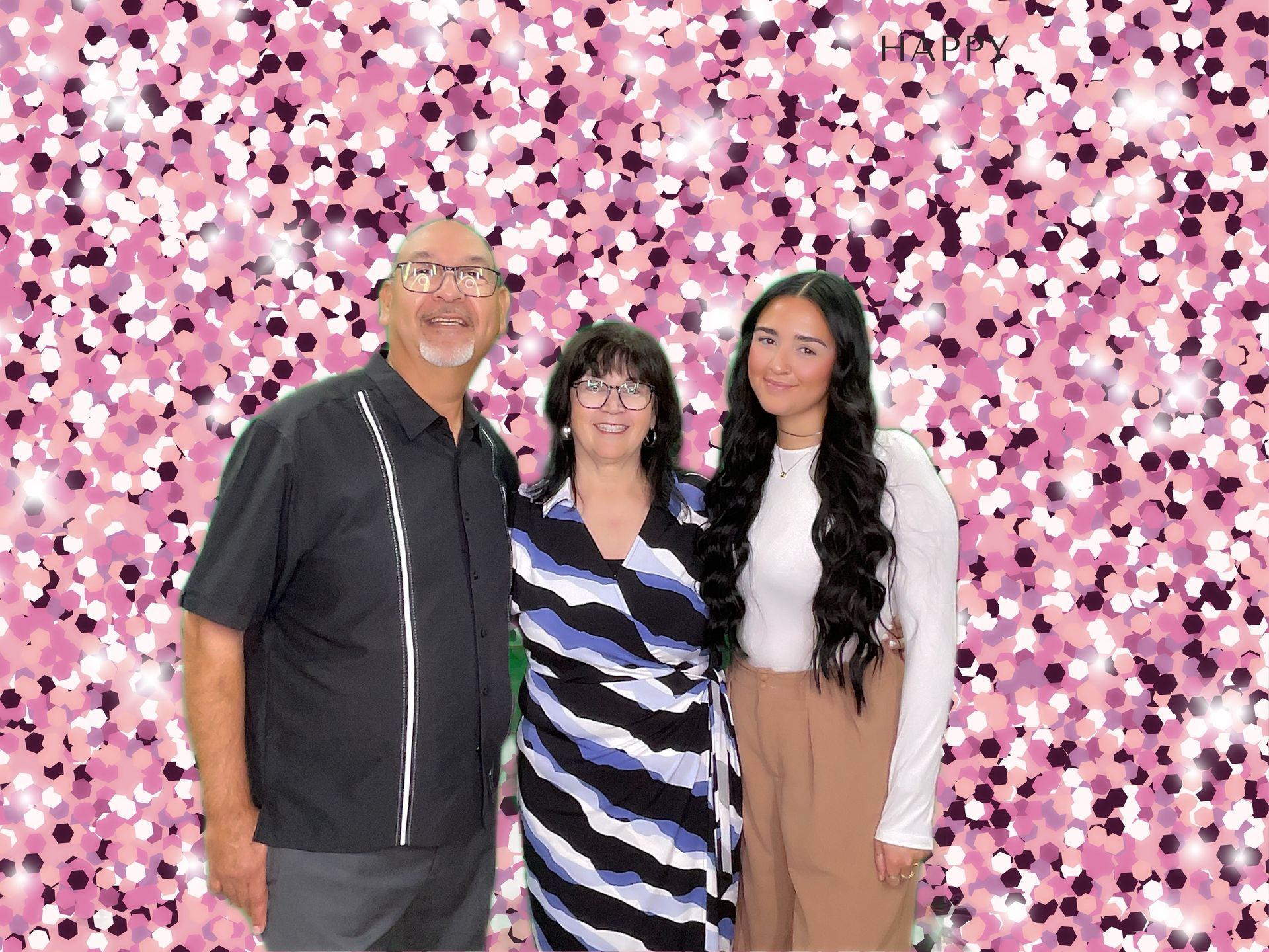 A family is posing for a picture in front of a pink background.