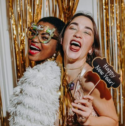 Two women holding a sign that says happy new year