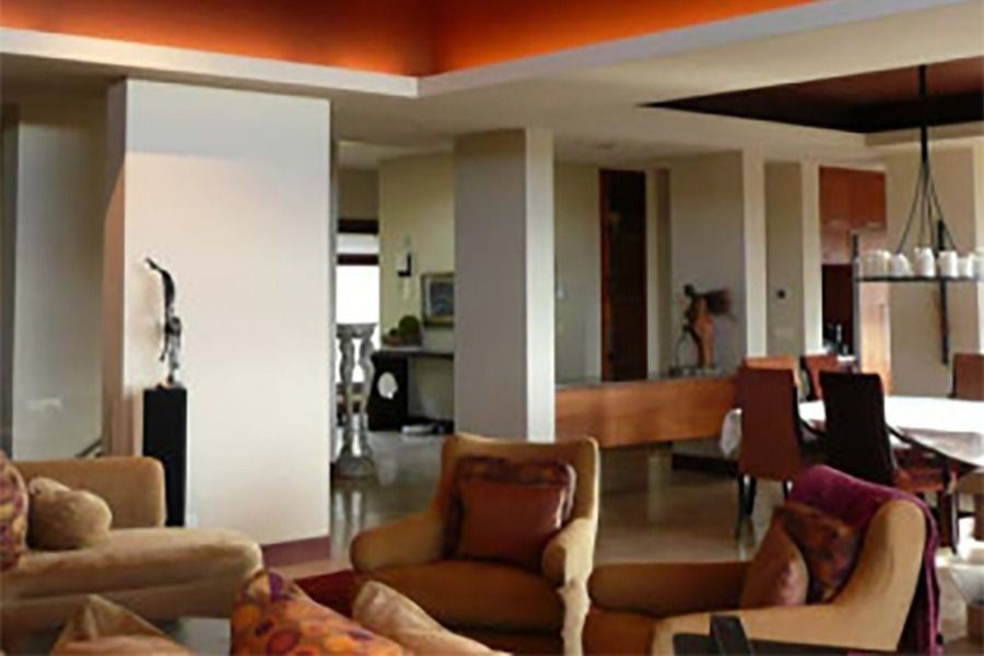 Spacious interior living space with beige walls, orange ceiling accent, and various seating areas.