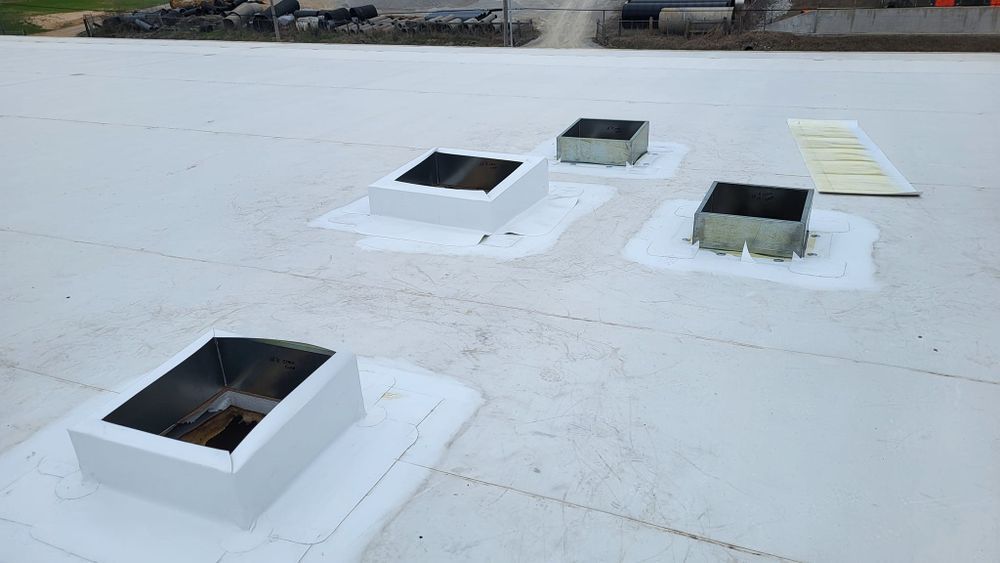 White commercial roof with four vents and a rectangular panel.