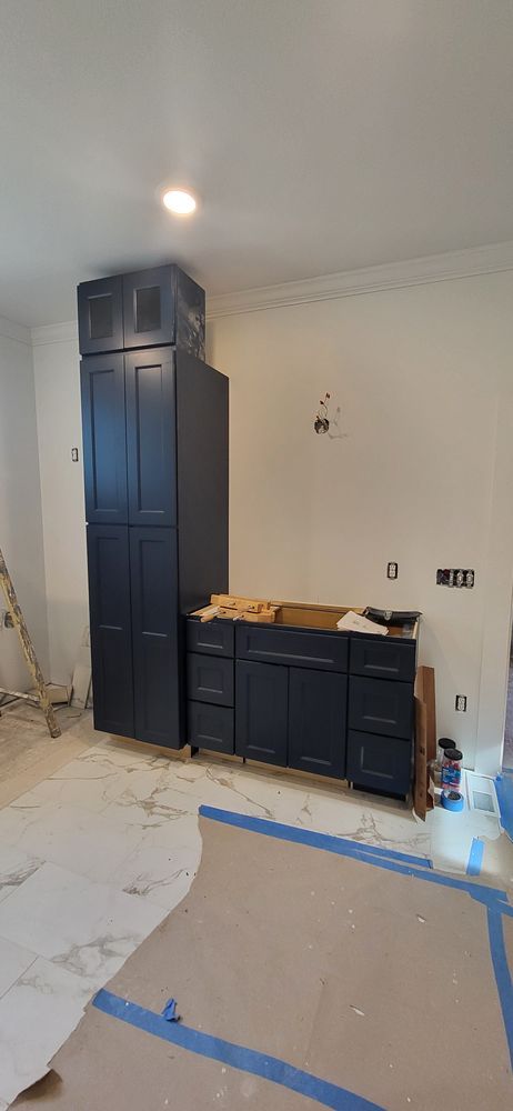 Dark blue kitchen cabinets in a room under construction.